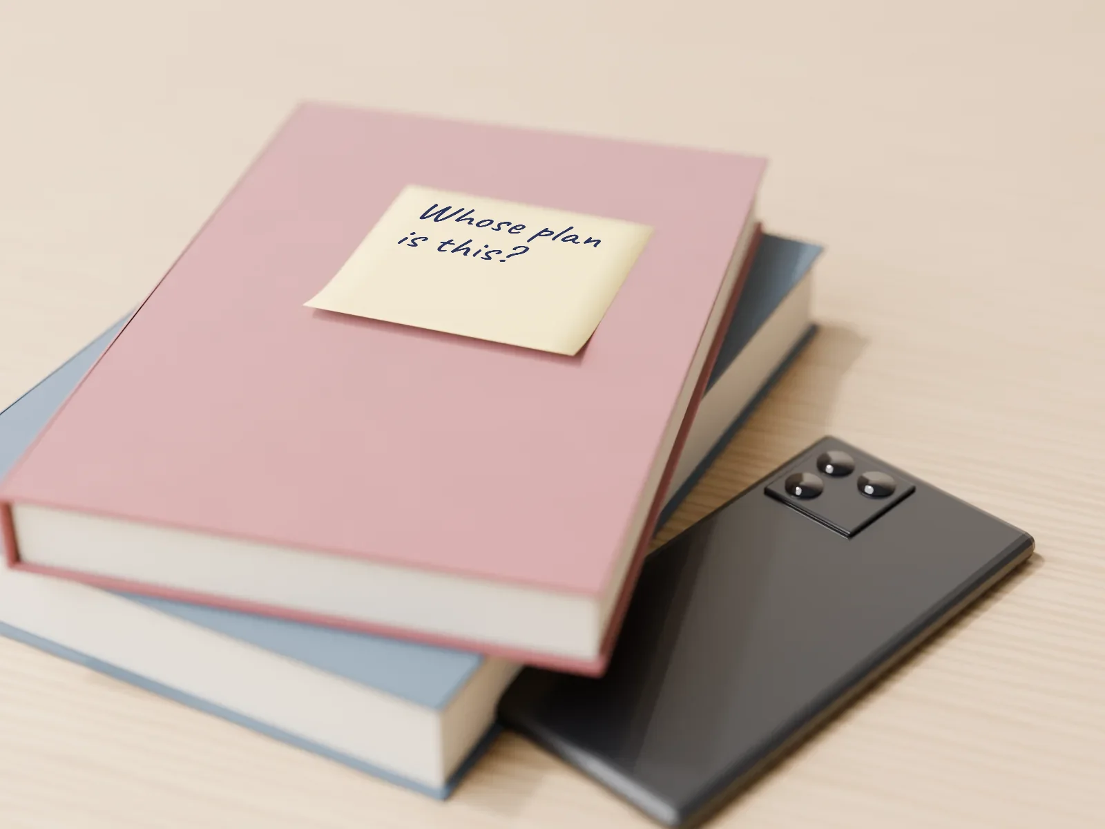 Two cloth-bound books with a phone face down beside them. A sticky note on the top book asks: Whose plan is this?